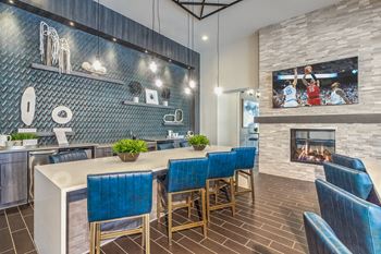 A modern kitchen with blue chairs and a fireplace